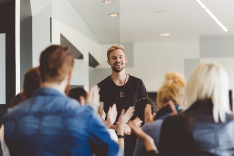 a person standing in front of a group of people clapping