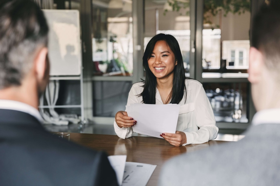 a person smiling at a table with papers